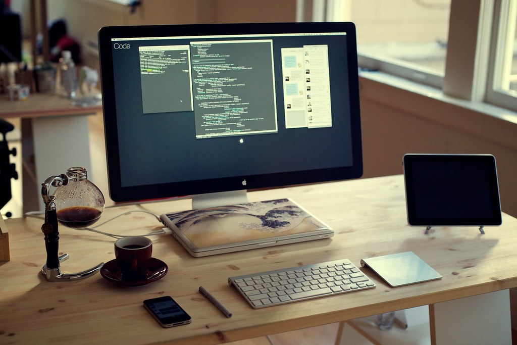 A person working at a laptop from a home desk in warm afternoon light.