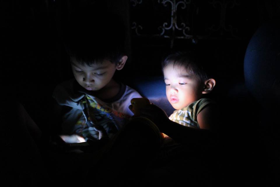 A player holding a phone at night, lit by the warm glow of the screen.