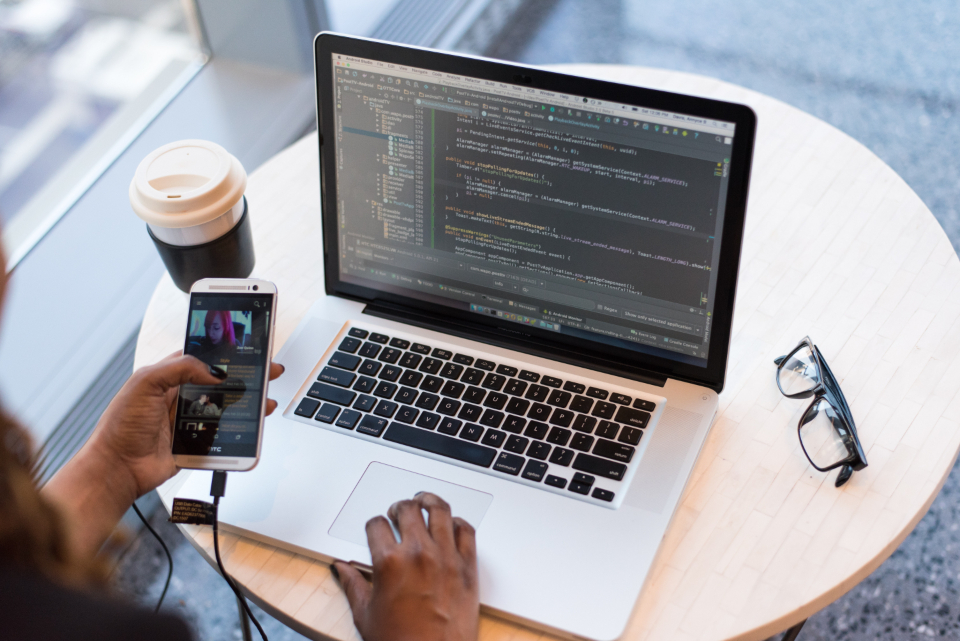 A developer working at a warm, sunlit desk, integrating a payments SDK on a laptop.