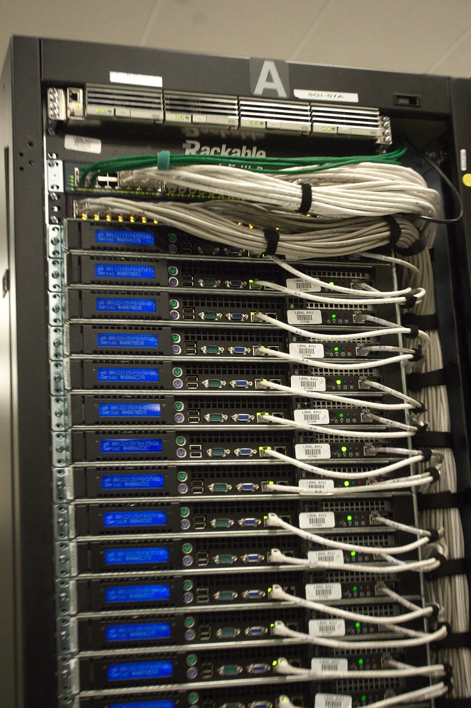 A dark data center aisle lit with blue and teal indicators